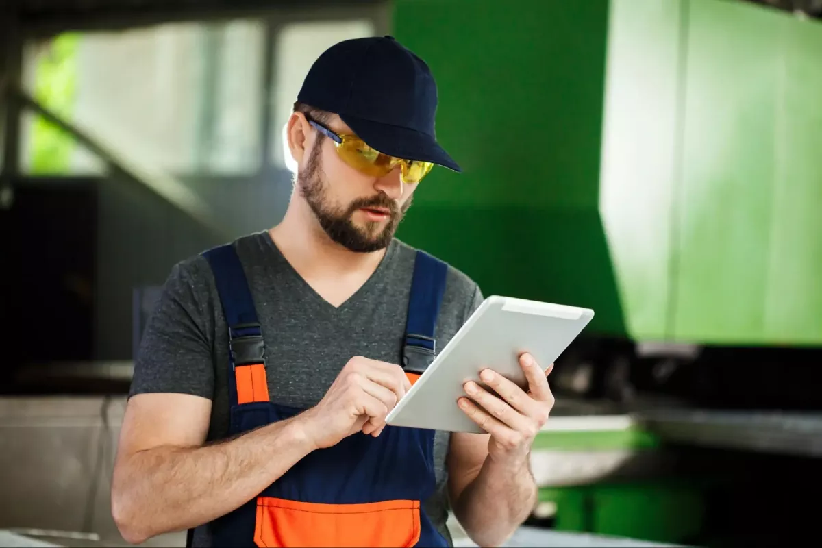 Travailleur FSM en tenu de travail regarde une tablette pour une démarche RSE/QSE